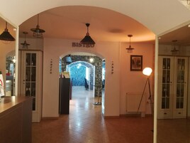 A corridor with an arched entrance labeled "BISTRO" leading to a room with a blue wall decorated with words like "LOVE" and "BIG." There are pendant lights above the corridor and a floor lamp to the right.