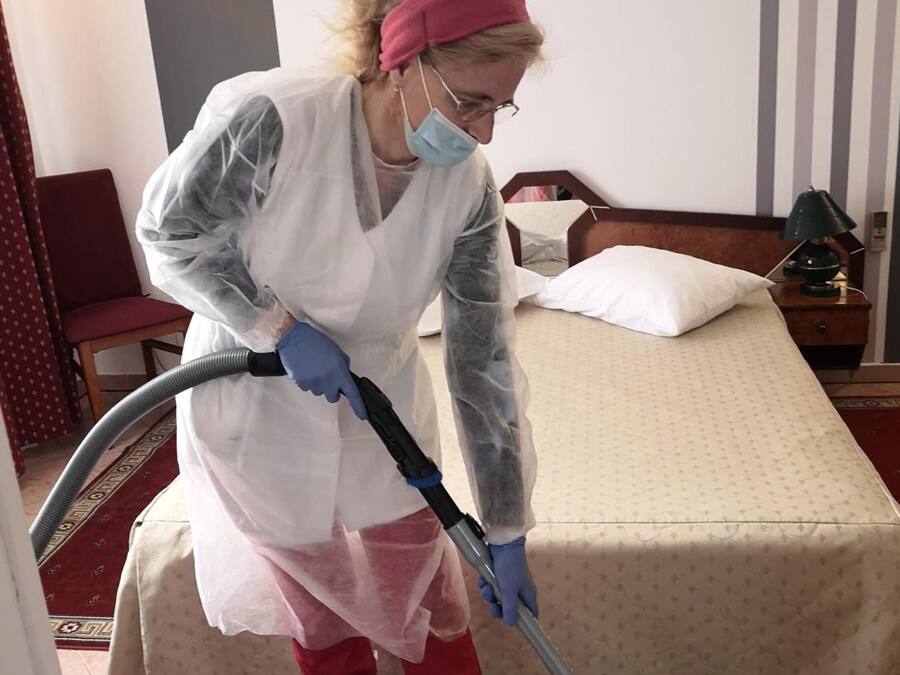 A person cleaning a hotel room with a vacuum cleaner.