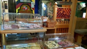 Zona de bufé con diversos alimentos presentados en recipientes transparentes.