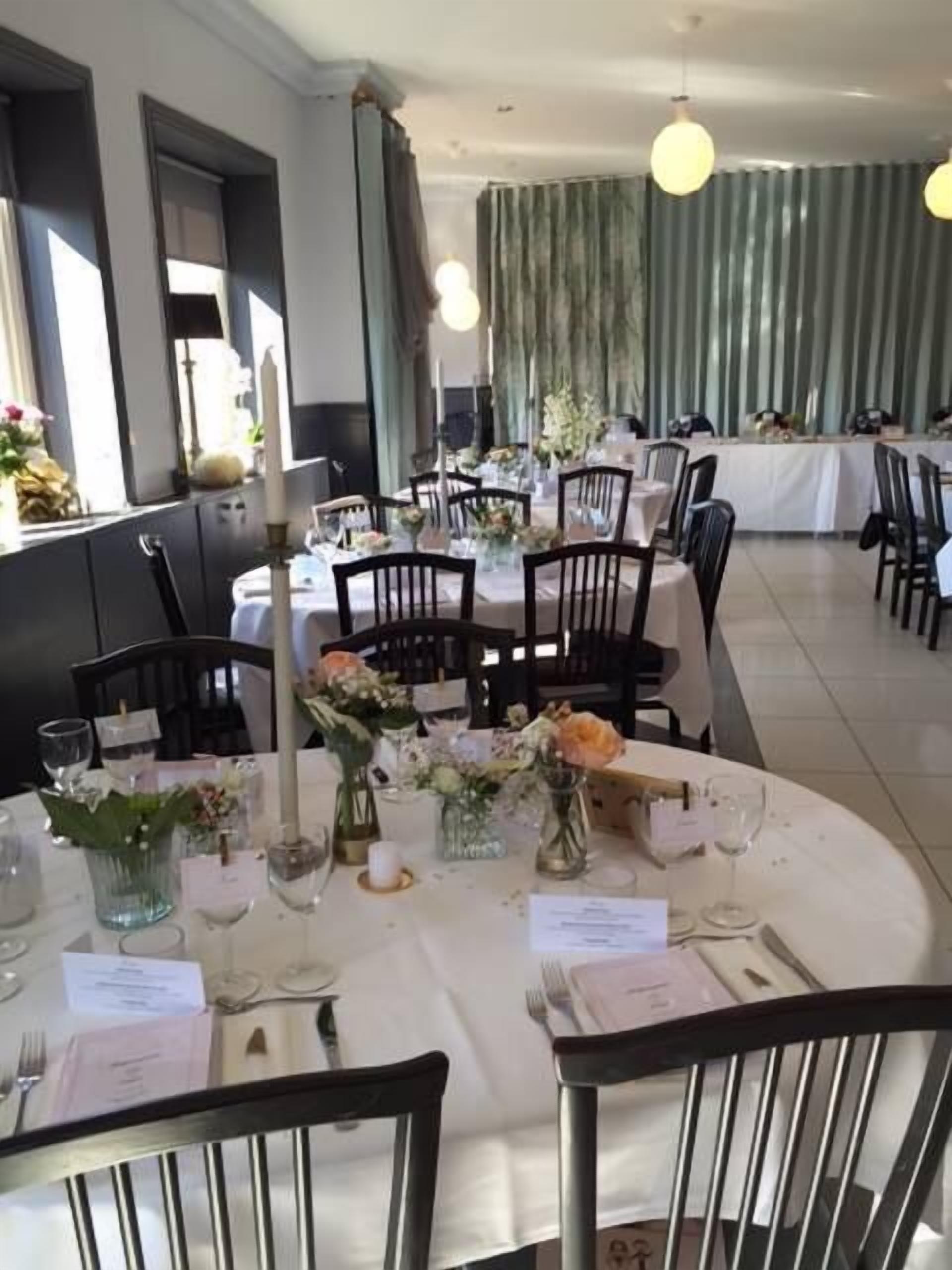 A formal dining area with round tables, chairs, and floral centerpieces.
