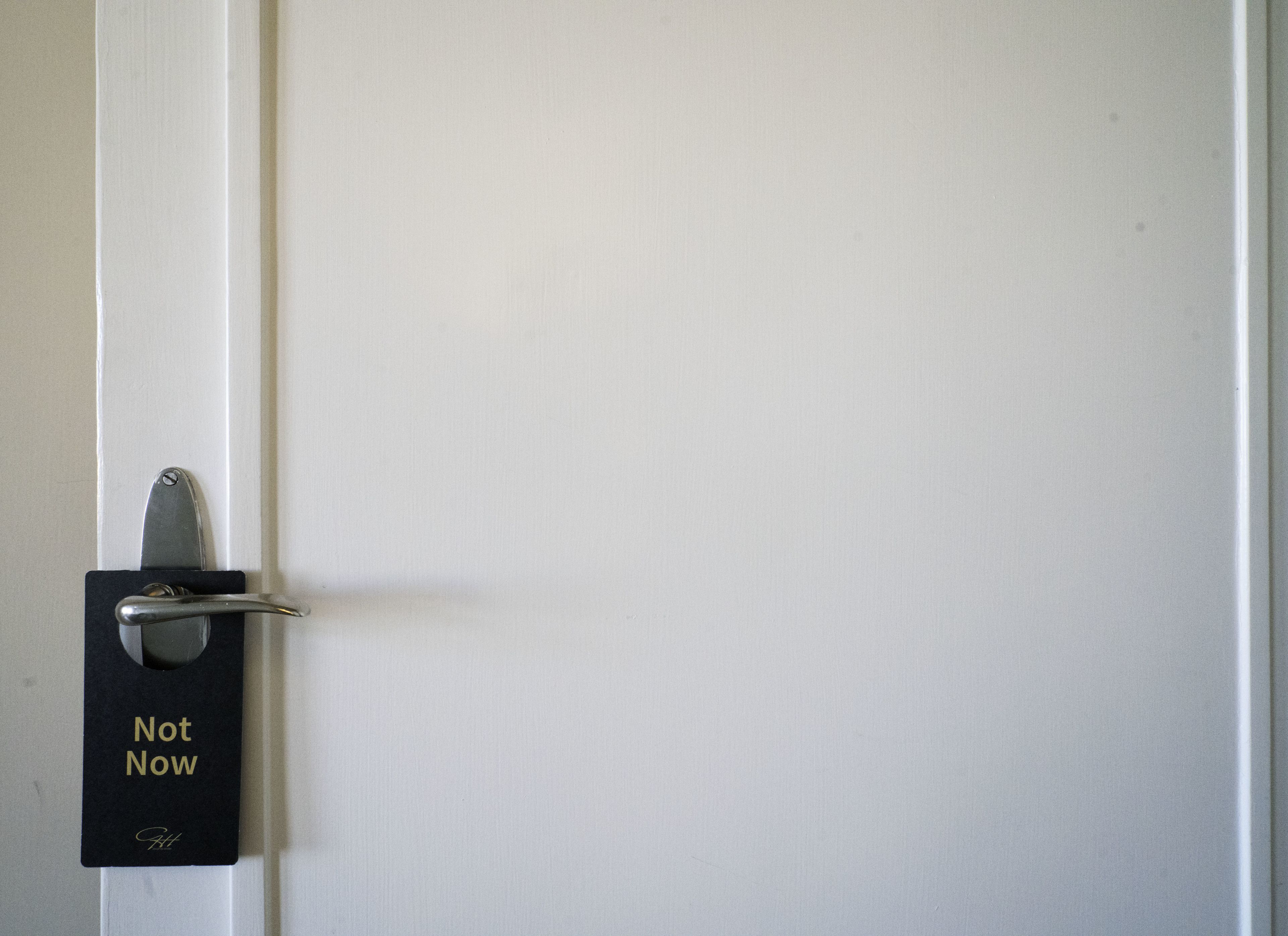 A door with a "Not Now" sign on a black plate.