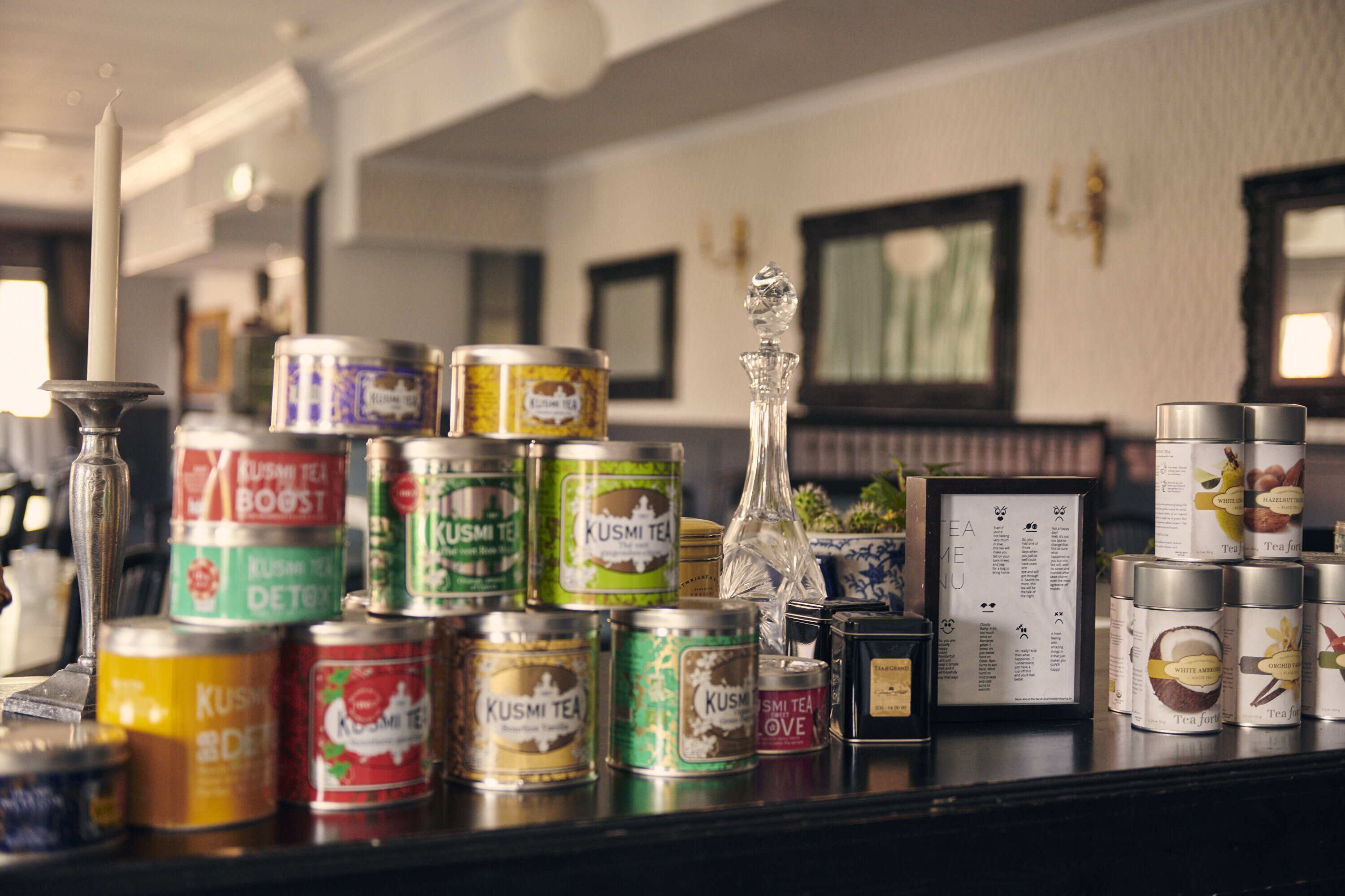 Variedad de latas de té y una vela sobre una encimera.