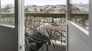 Un balcón con vistas a un paisaje urbano, una mesa con aperitivos y una botella de vino.