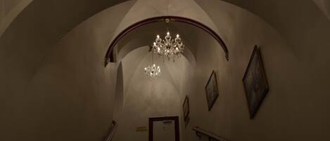 Eine prachtvolle Treppe mit einer Chandelier, gerahmten Kunstwerken und einem Schild, das ein Restaurant anzeigt.