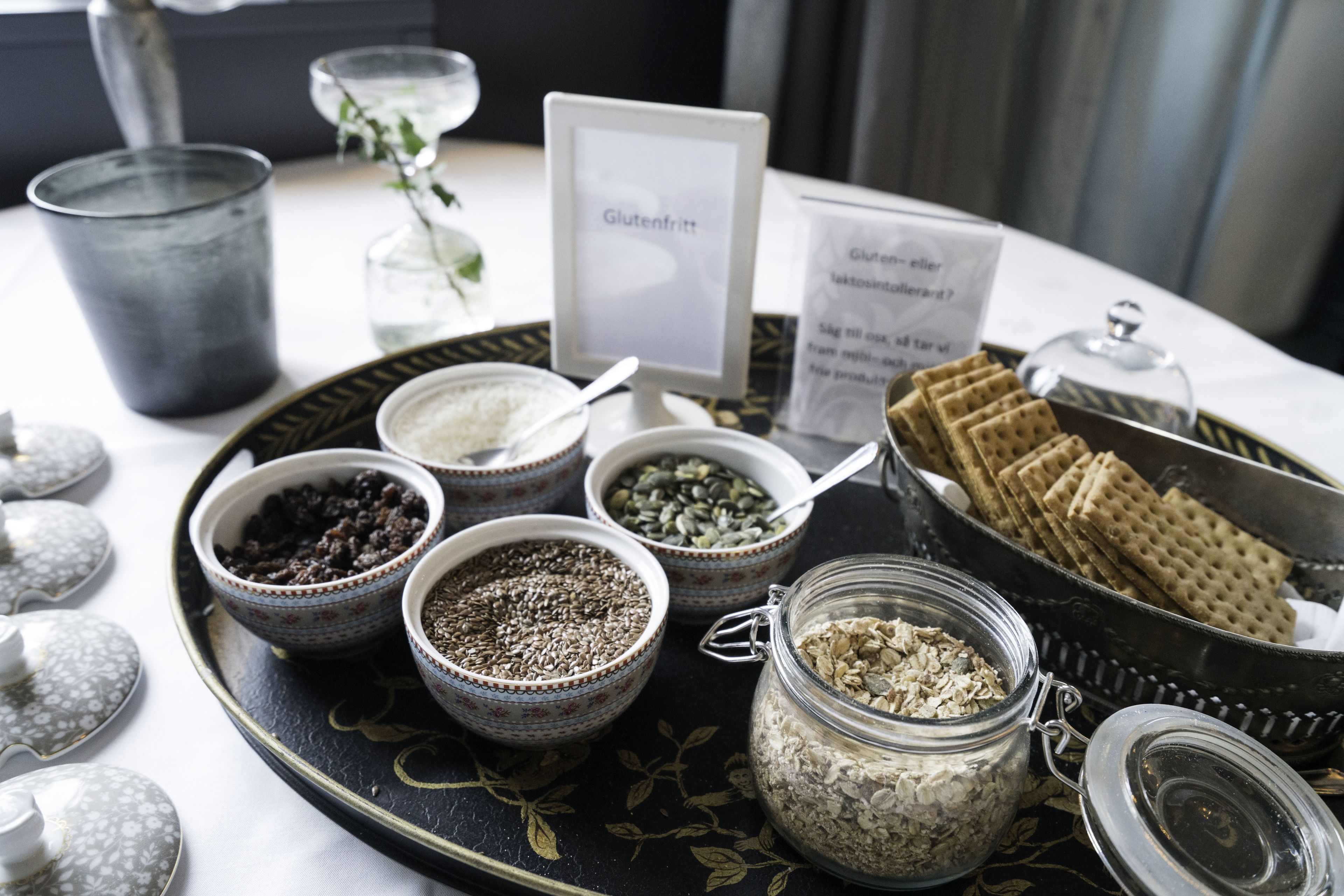 A tray with various food items including seeds, grains, and crackers, with labels indicating gluten-free options.
