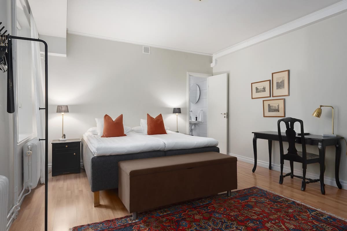 A bedroom with a bed, bedside tables, a desk, and a chair.