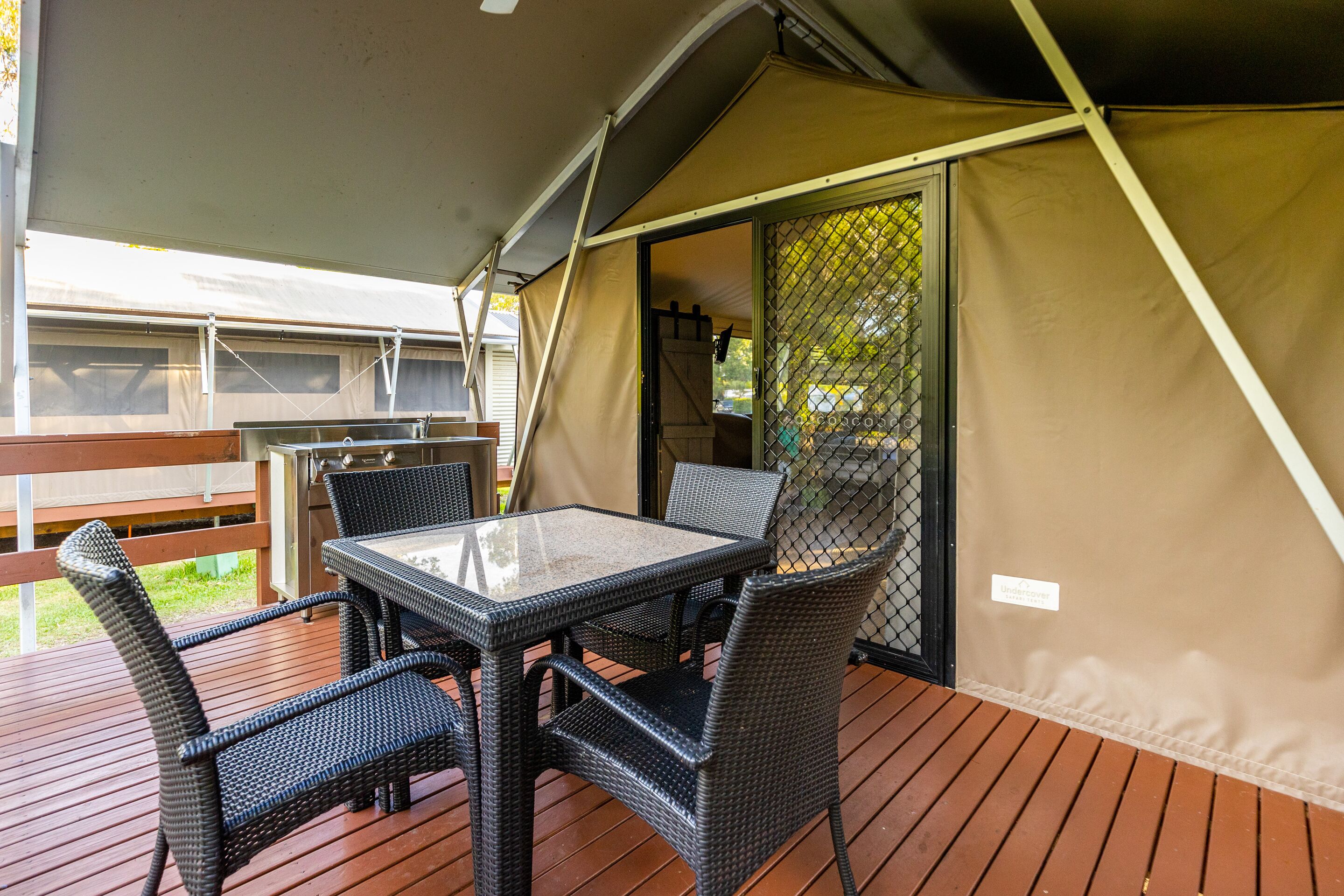 A covered outdoor seating area with a table and chairs, a wooden deck, and a tent structure.