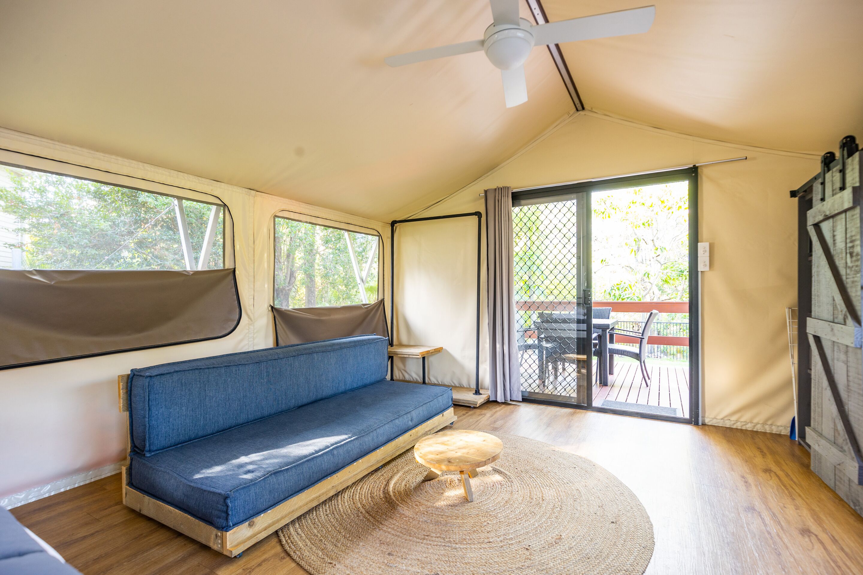 A cozy interior with a blue sofa, a small wooden table, and a ceiling fan.
