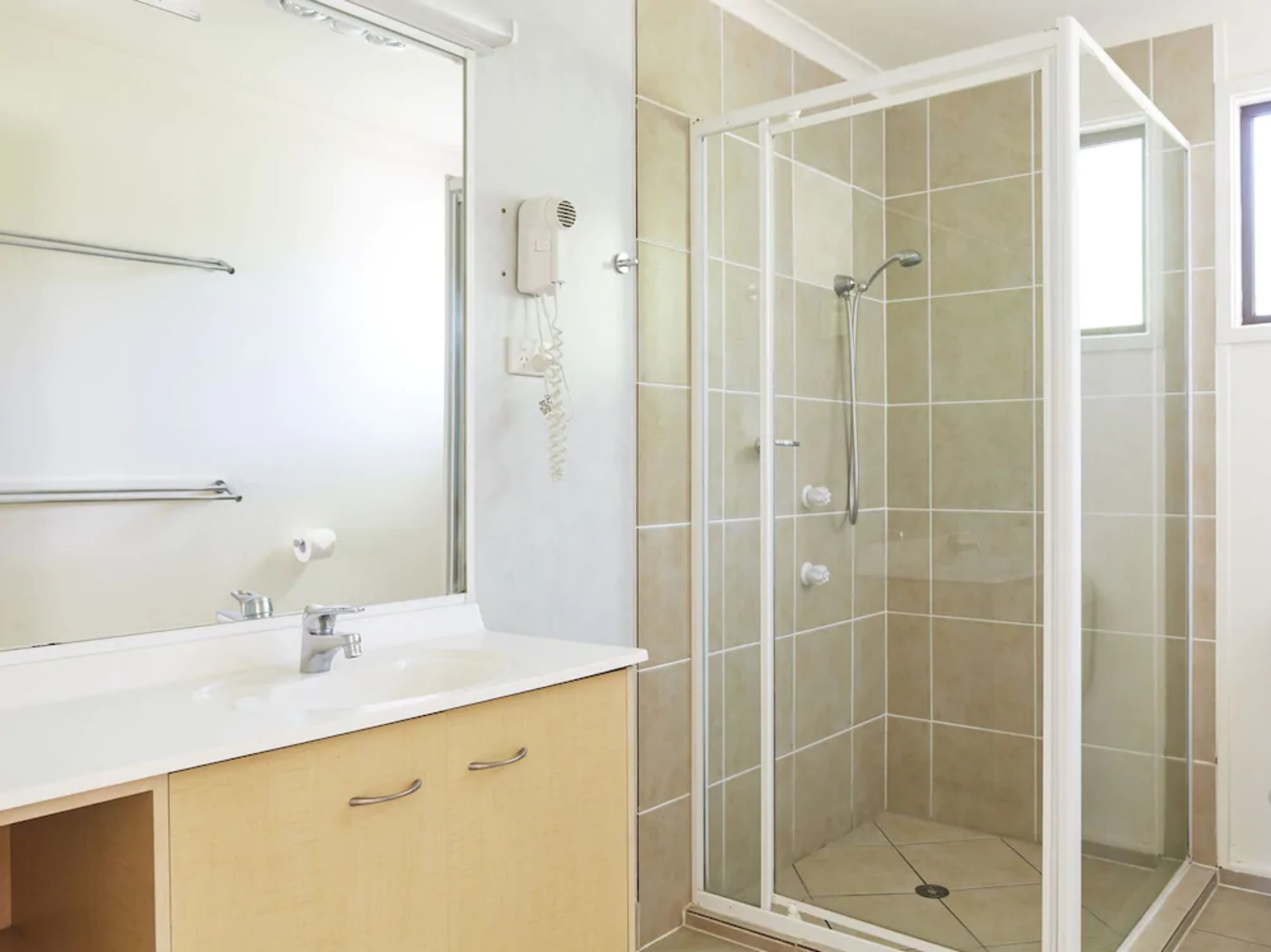 A bathroom with a glass-enclosed shower, a white sink, and a mirror.