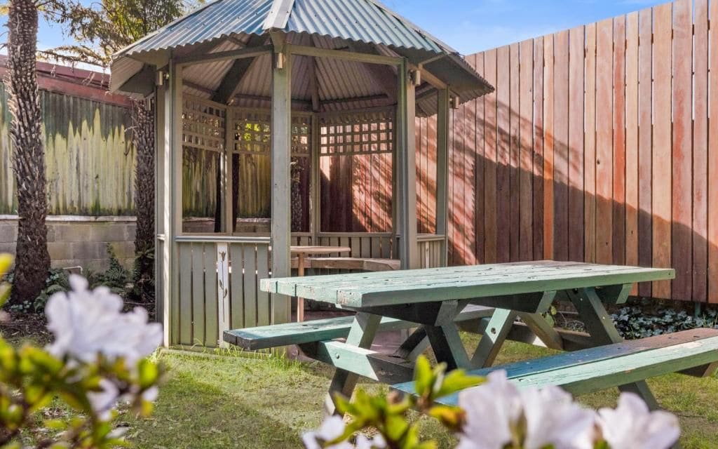Ein Pavillon mit Metalldach und einem Holzzaun im Hintergrund.