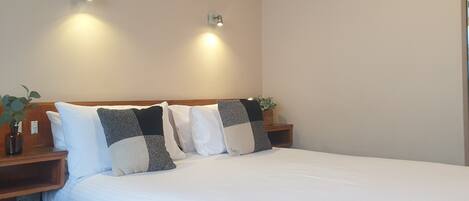 A neatly made bed with white bedding, two bedside tables with lamps, and a wooden headboard.