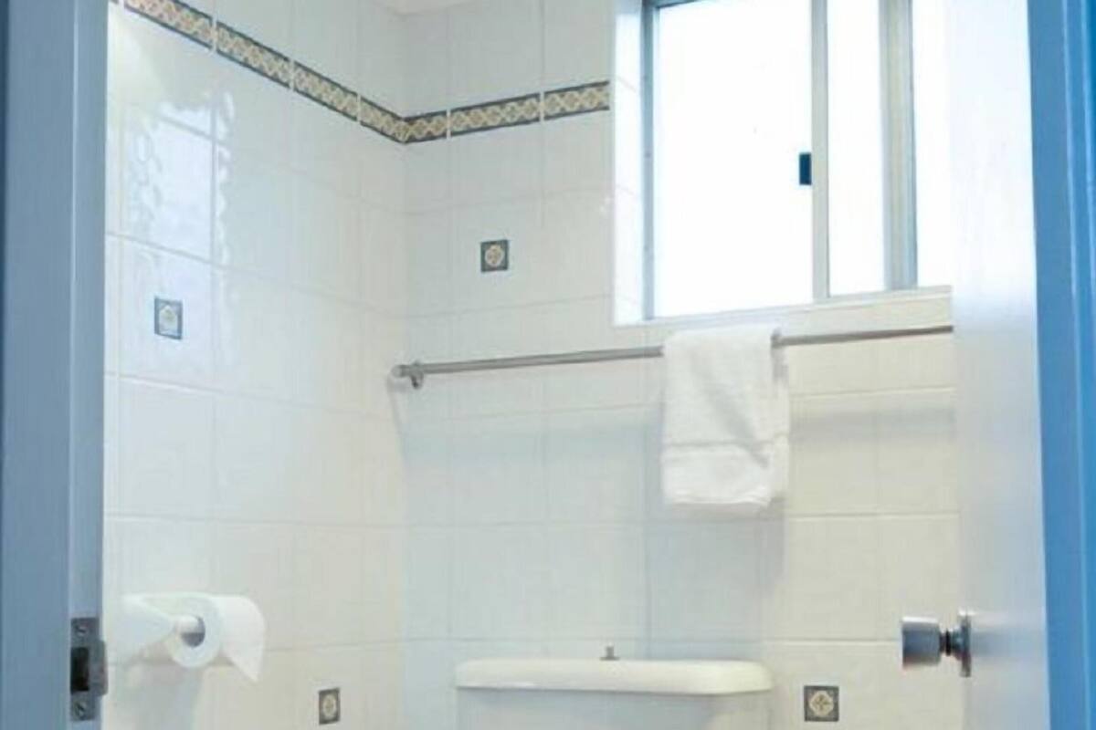 Ein kleines, sauberes Badezimmer mit Toilette, Waschbecken und Fenster.