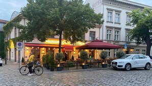 A restaurant with outdoor seating, a bicycle parked nearby, and a car parked on the street. - Altstadt Hotel (Potsdam)