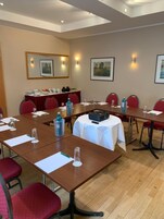 A conference room with multiple tables, chairs, and a projector.