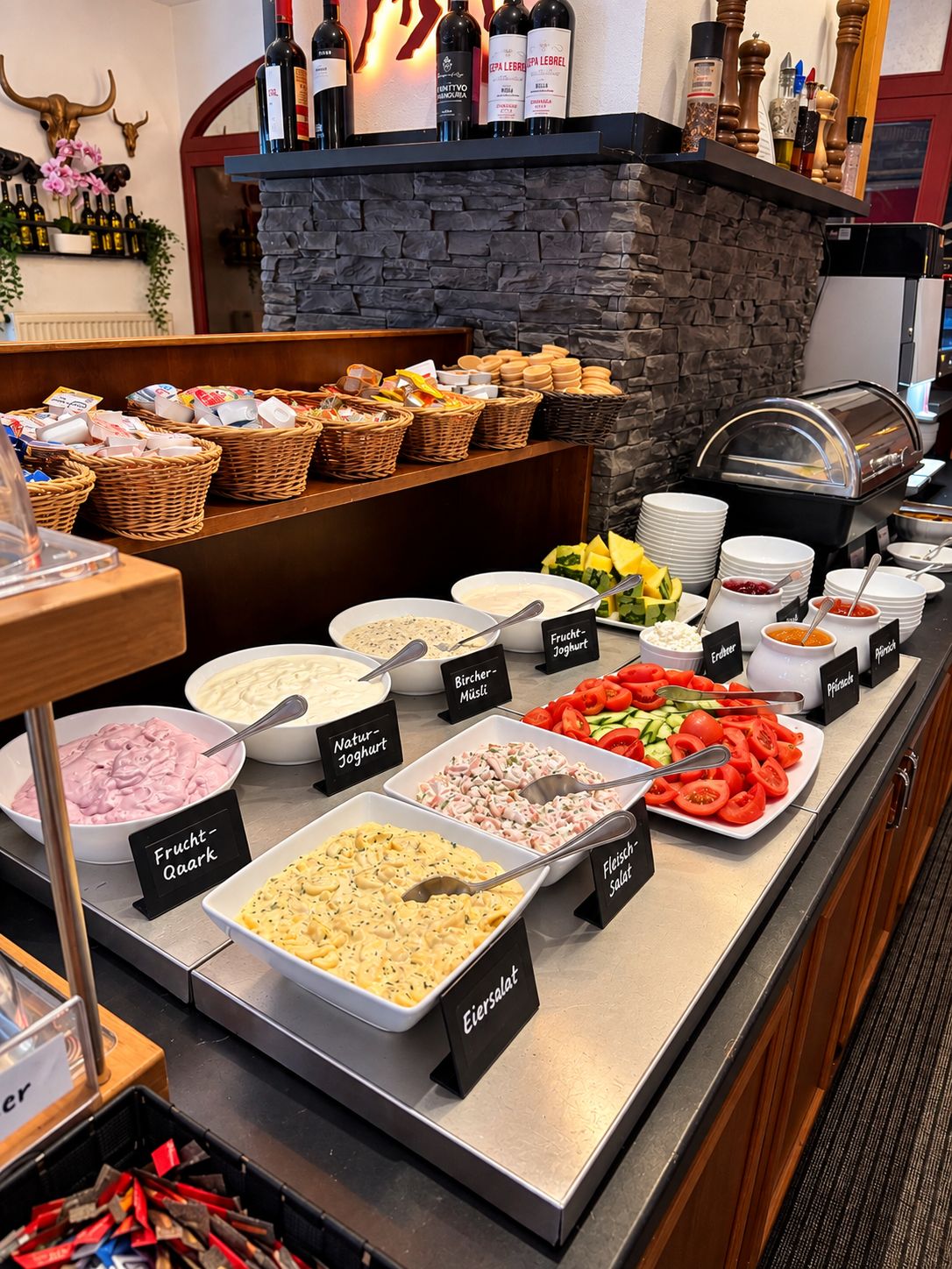 Ein Buffet mit verschiedenen Speisen, darunter Salate, Joghurts und Obst.