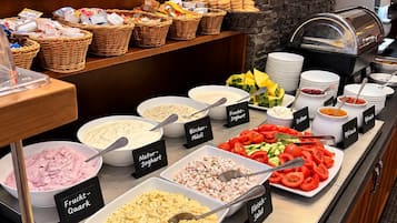 Ein Buffet mit verschiedenen Speisen, darunter Salate, Joghurts und Obst.