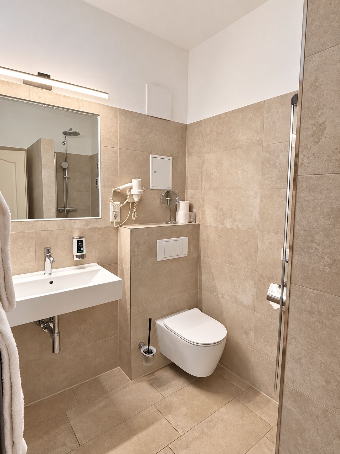 A modern bathroom with a sink, mirror, toilet, and shower.