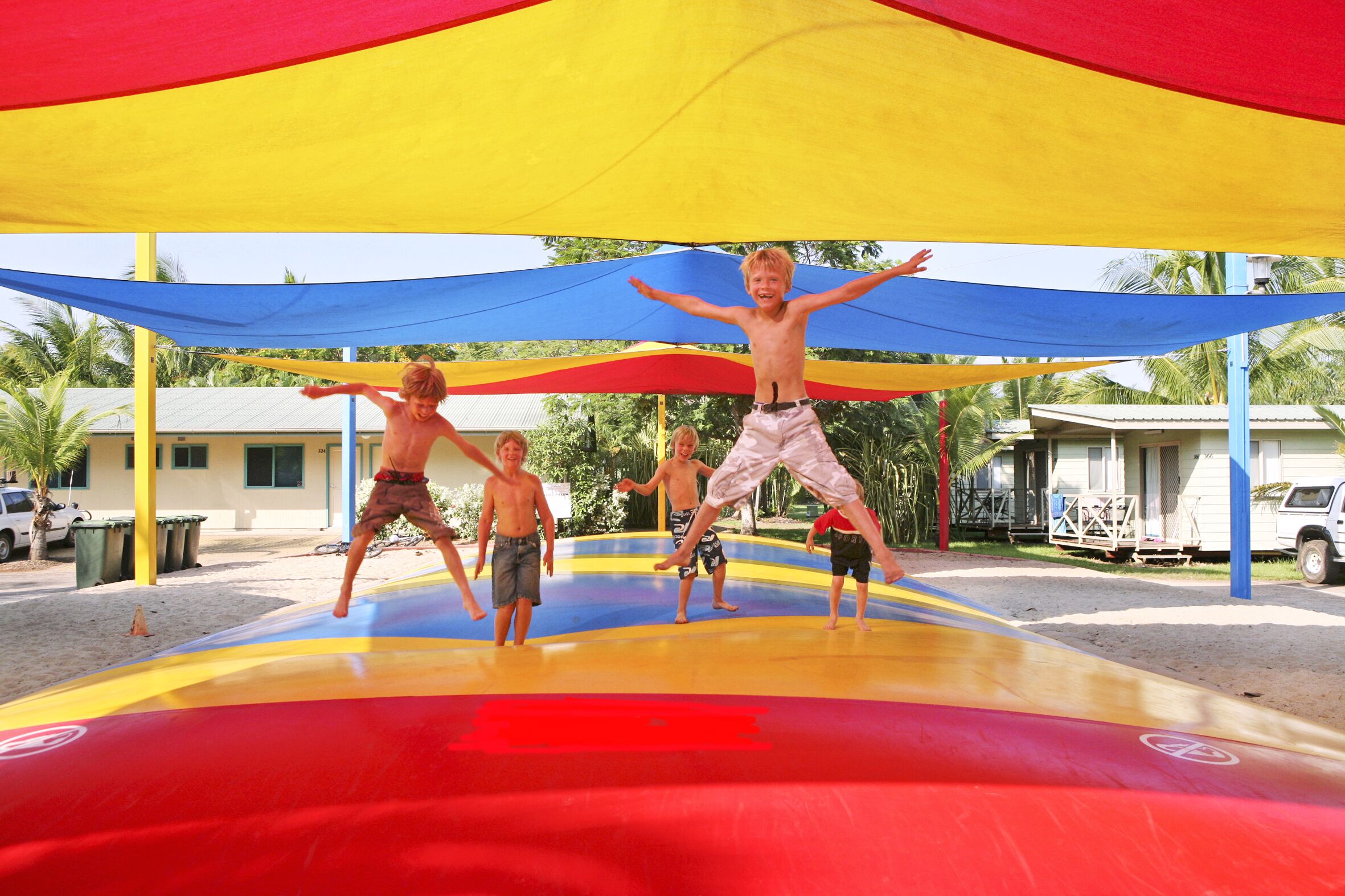 A group of children playing on a colorful inflatable structure under a canopy.