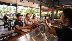 A bar area with a counter, bar stools, and a beer tap. - Darwin FreeSpirit Resort (Holtze)
