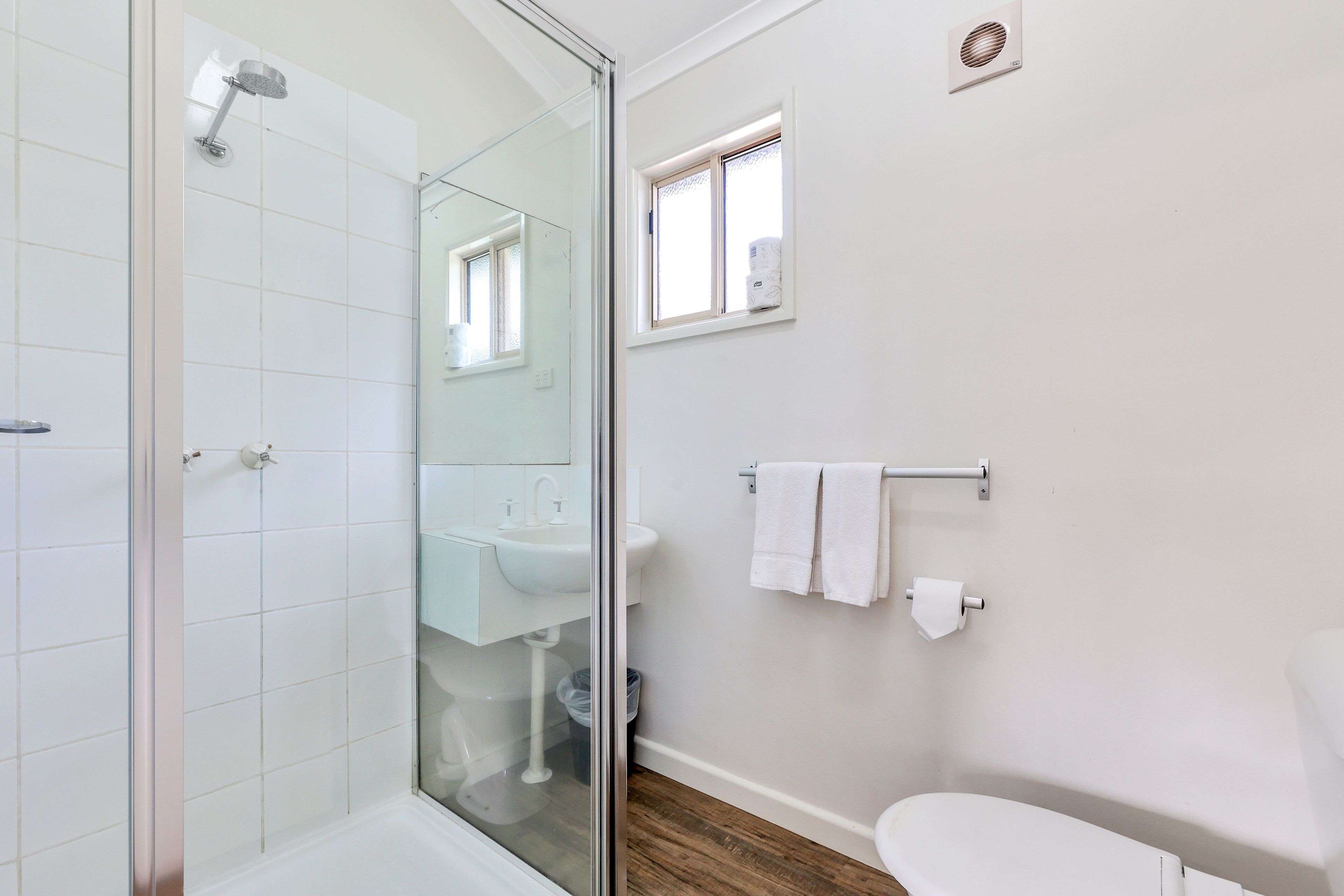 A modern bathroom with a glass shower enclosure, a white sink, and a toilet.