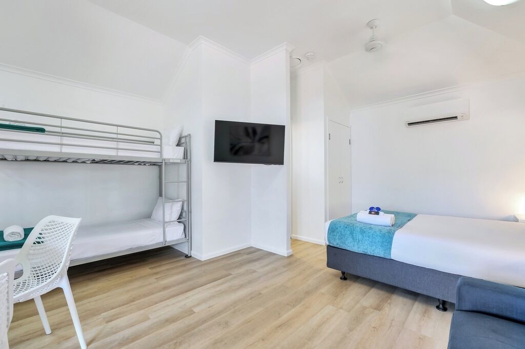 A room with bunk beds, a desk, a chair, a bed, and a TV.