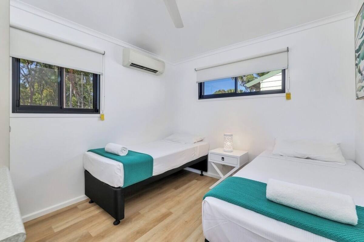 Una habitación con dos camas, una ventana y un equipo de aire acondicionado.