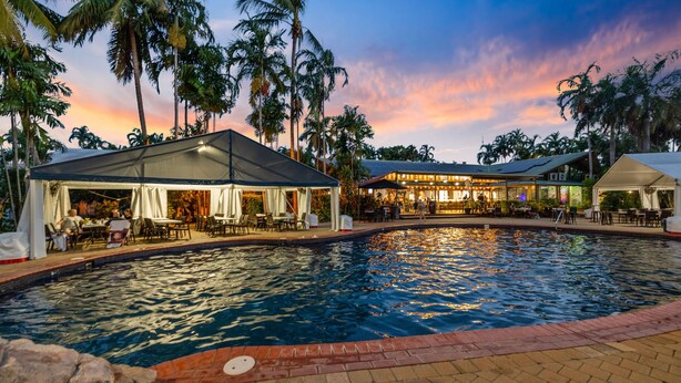 A pool area with a covered seating area and a building with outdoor seating. - Darwin FreeSpirit Resort (Holtze)