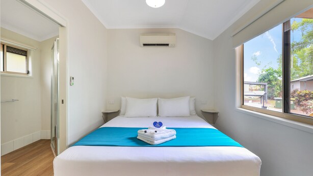 A hotel room with a bed, a window, and an air conditioning unit. - Darwin FreeSpirit Resort (Holtze)