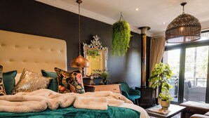A modern bedroom with a large bed, a hanging plant, and a view of the outdoors. - Sw1 Lodge (Cape Town)