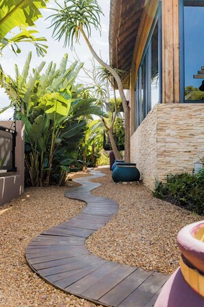 A pathway leading to a building with a stone facade and large windows.