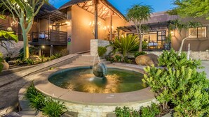 A courtyard with a circular water feature, a thatched-roof building, and lush greenery. - SW1 Lodge (Cape Town)