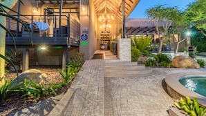 A modern hotel with a covered outdoor seating area, a pool, and a well-maintained garden. - SW1 Lodge (Cape Town)