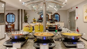 A buffet setup with various dishes, including scrambled eggs and a casserole, served on induction cooktops.