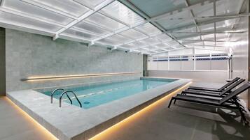 Una piscina techada, sillones reclinables de piscina