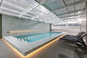 Una piscina techada, sillones reclinables de piscina