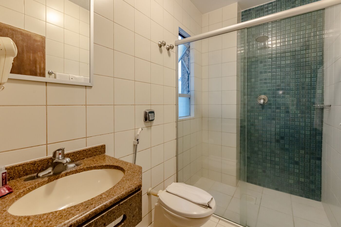 Un baño con lavamanos de granito, inodoro blanco y cabina de ducha de vidrio.