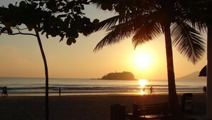 A beach scene with a sunset, palm trees, and a distant island.