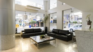 A modern lobby with black leather sofas, a glass coffee table, and a reception desk.