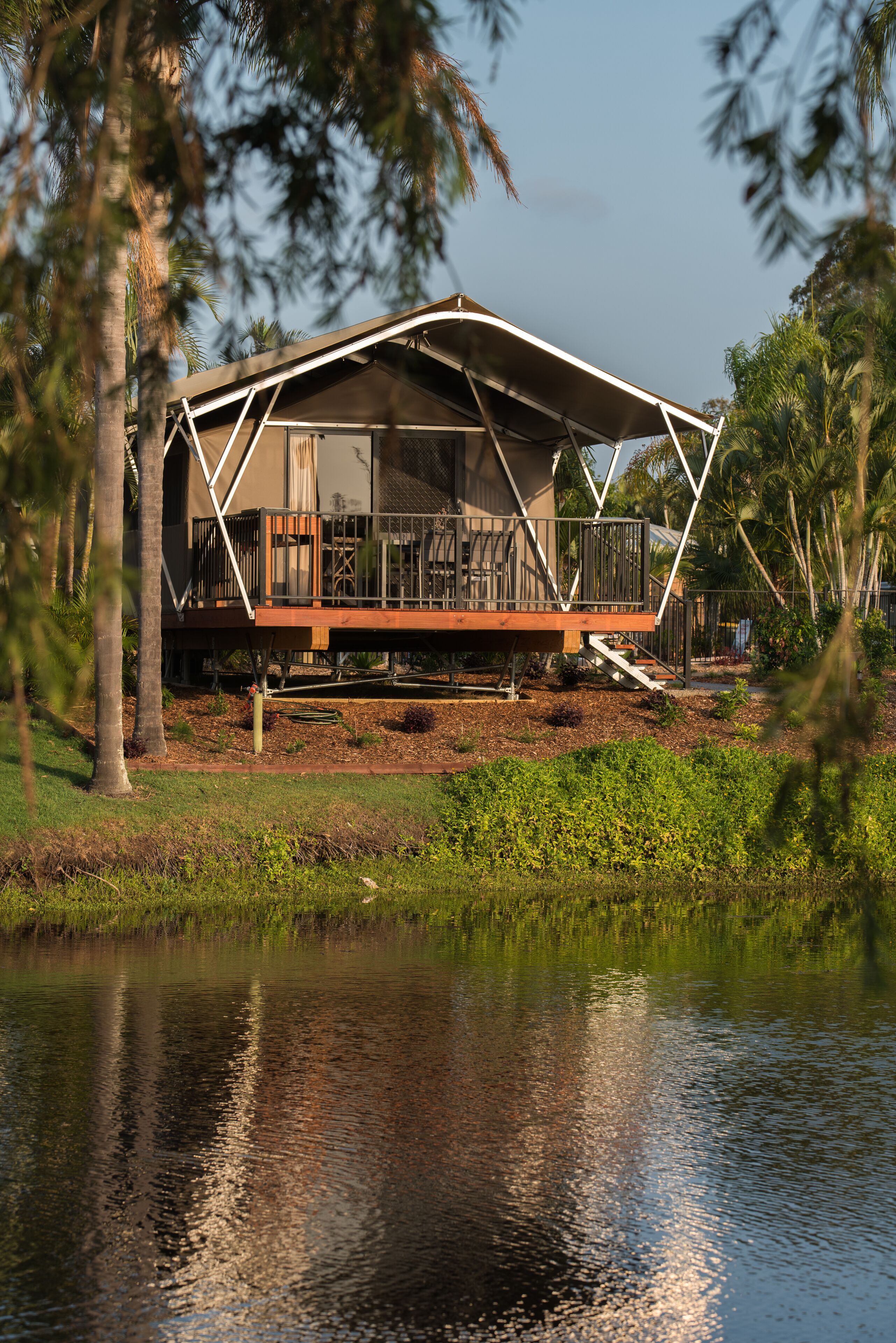 A modern house with a large deck, a covered outdoor area, and a view of a body of water.