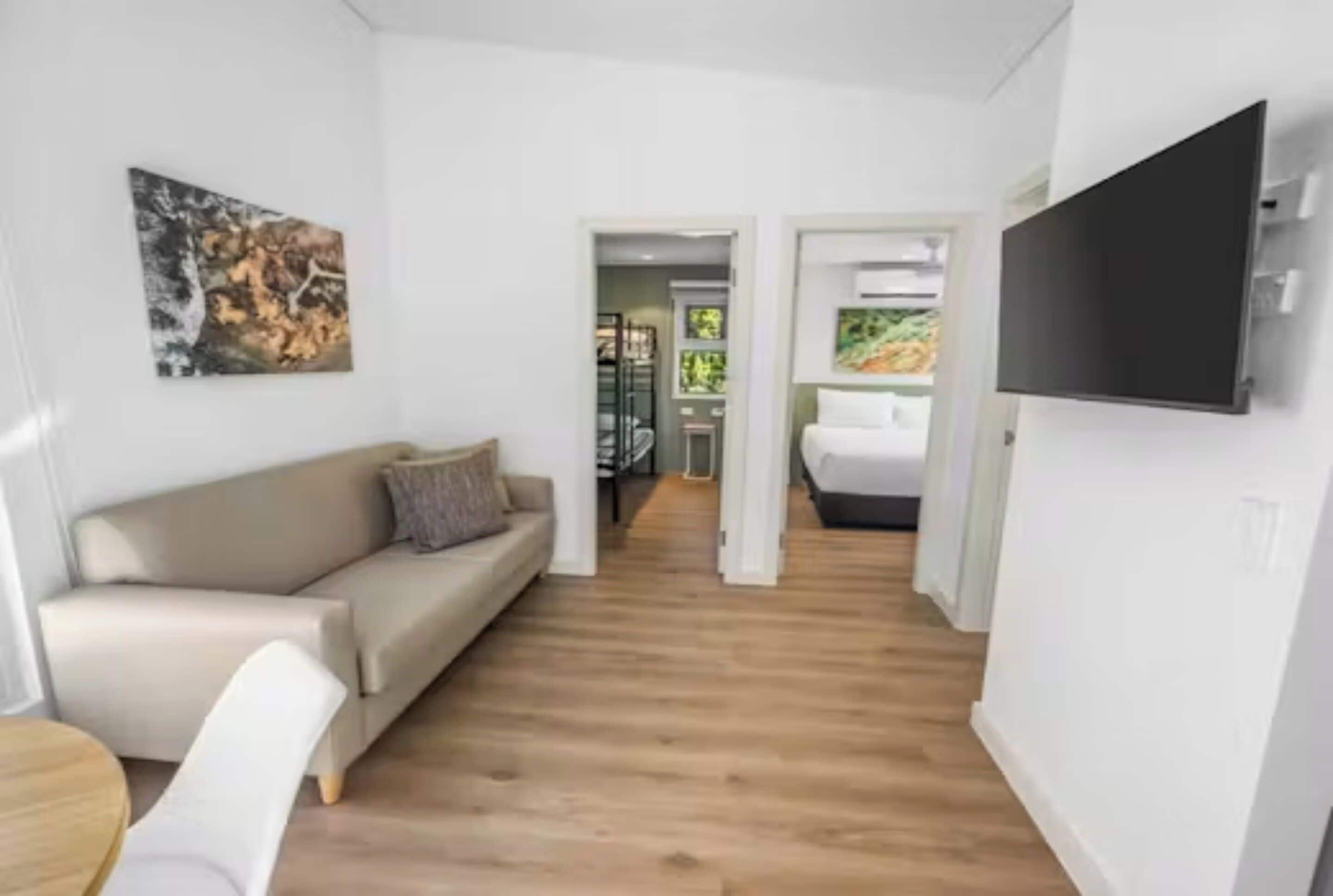 A modern interior with a sofa, a flat-screen TV, and a wooden floor.