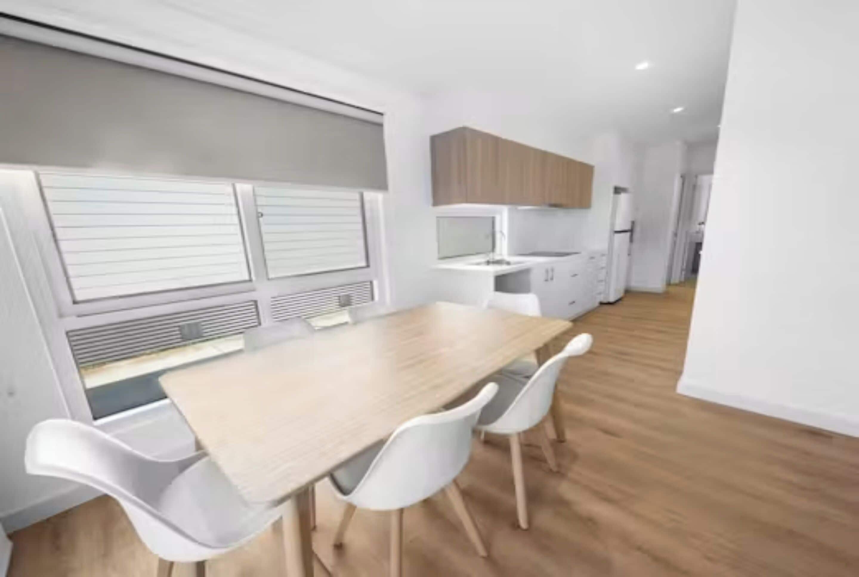 Una cocina moderna con armarios blancos, encimera de madera y horno empotrado.