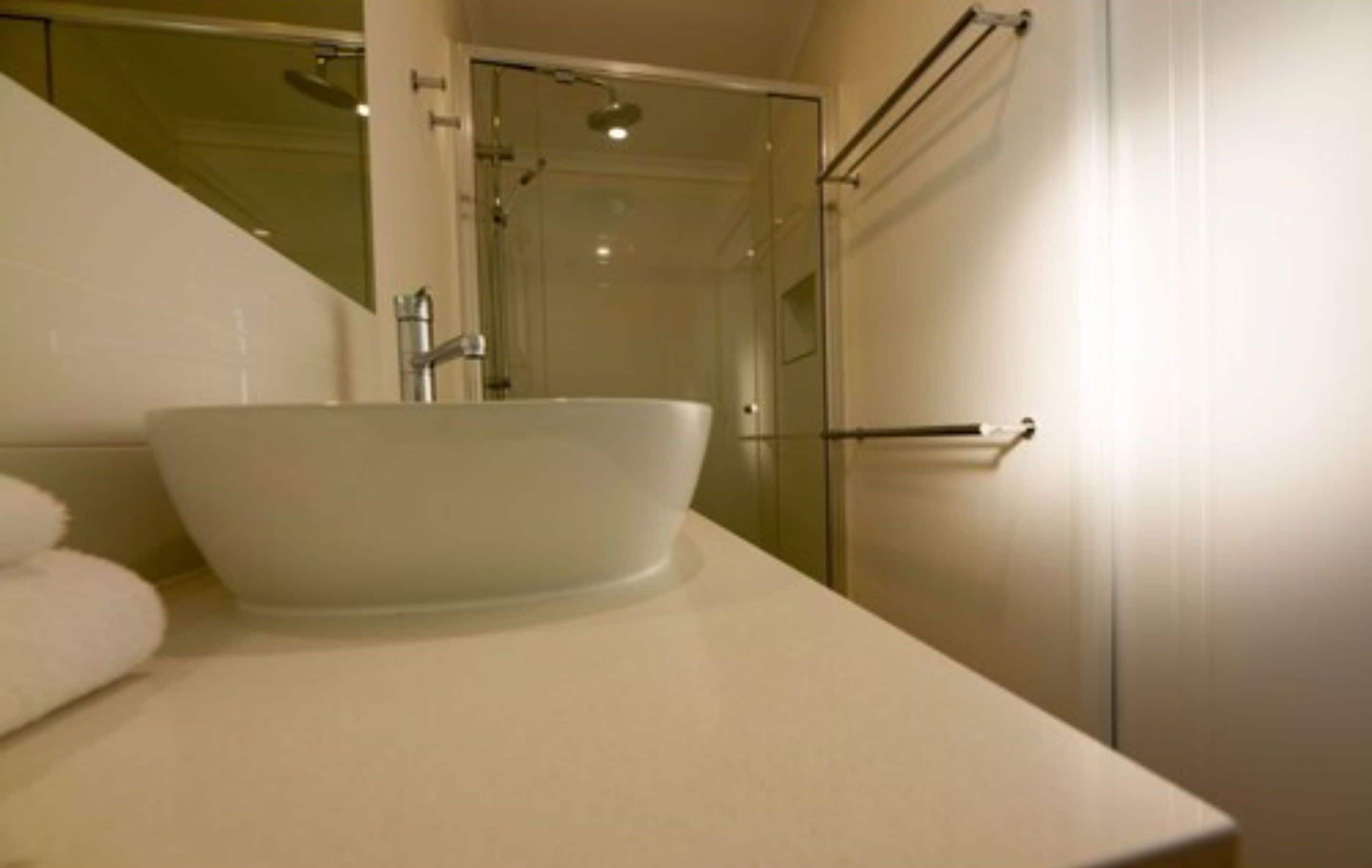 A bathroom with a white sink, a glass shower enclosure, and a towel rack.