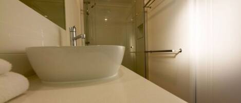 A bathroom with a white sink, a glass shower enclosure, and a towel rack.