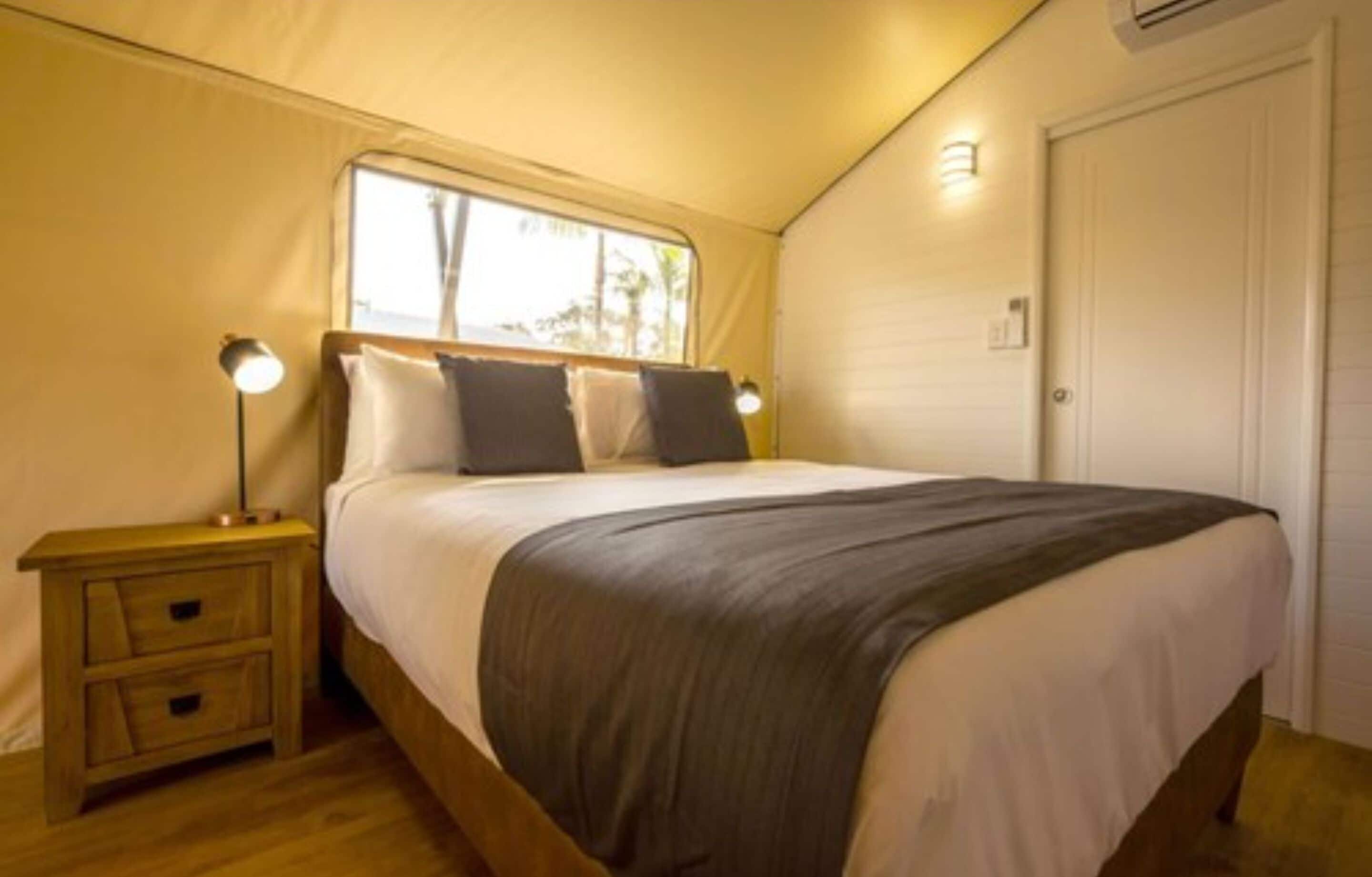 Un dormitorio con cama, lámparas de noche, una ventana y una puerta.