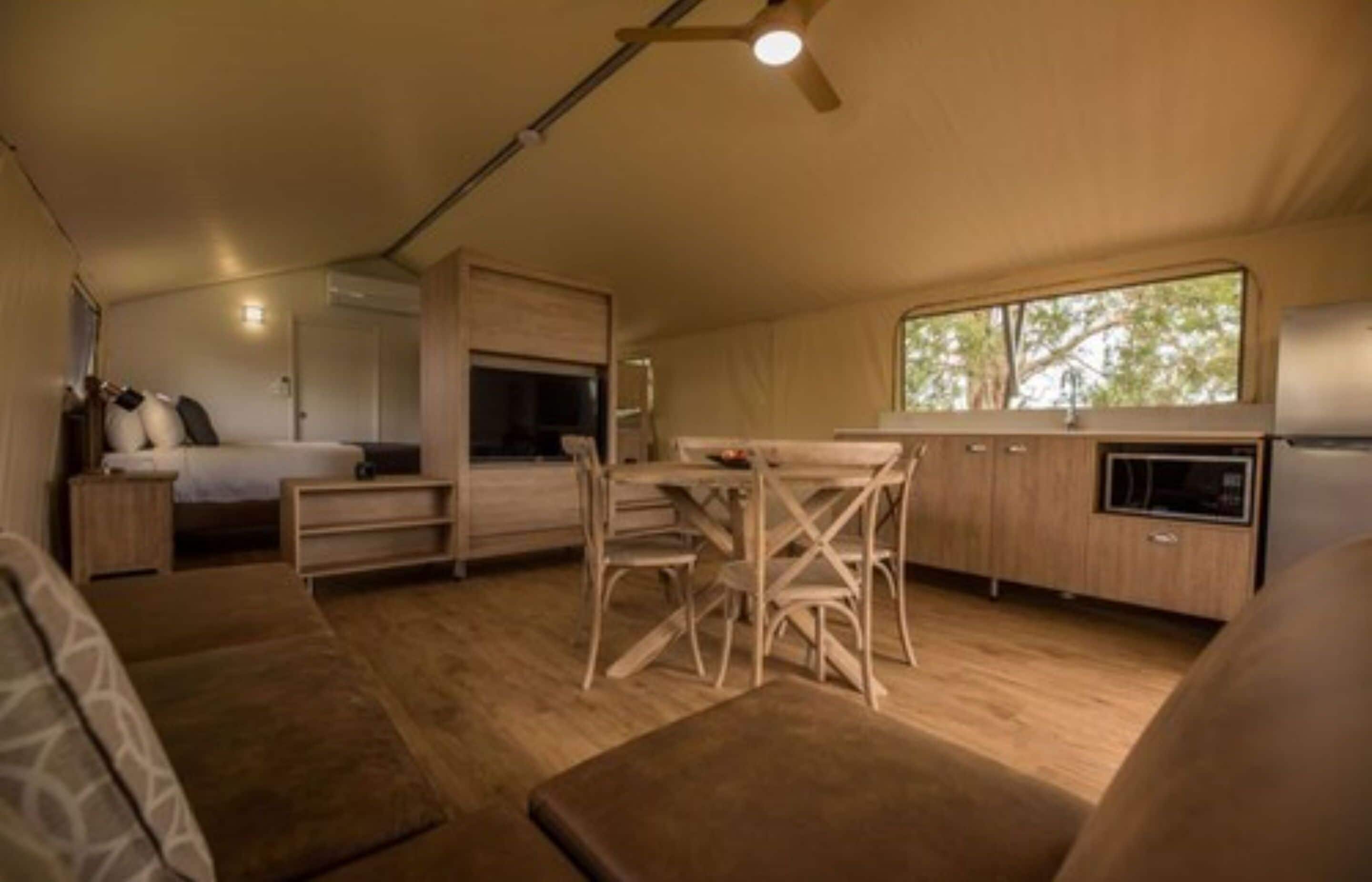 A compact, well-lit room with a kitchenette, a dining area, and a bed.