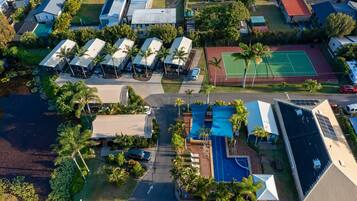 An aerial view of a residential area with multiple houses, a tennis court, and a swimming pool.