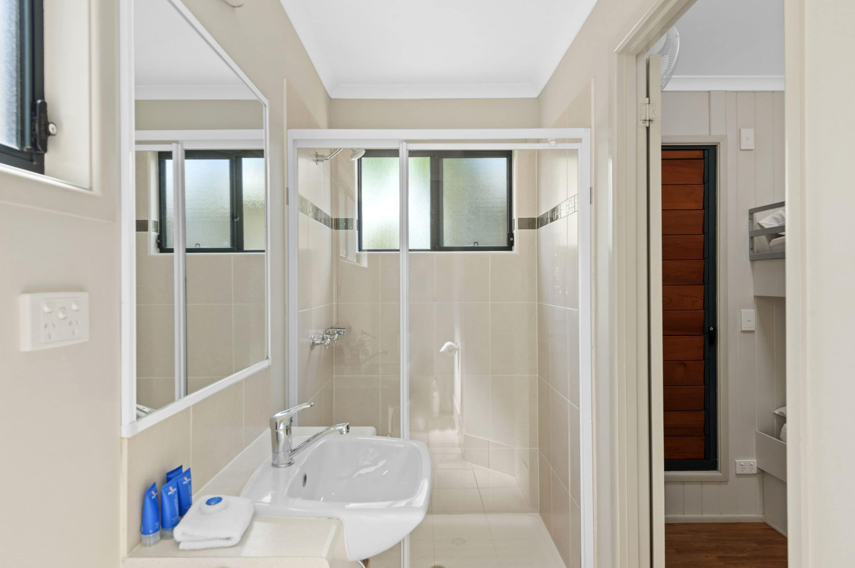A modern bathroom with a glass-enclosed shower, a white sink, and a mirror.