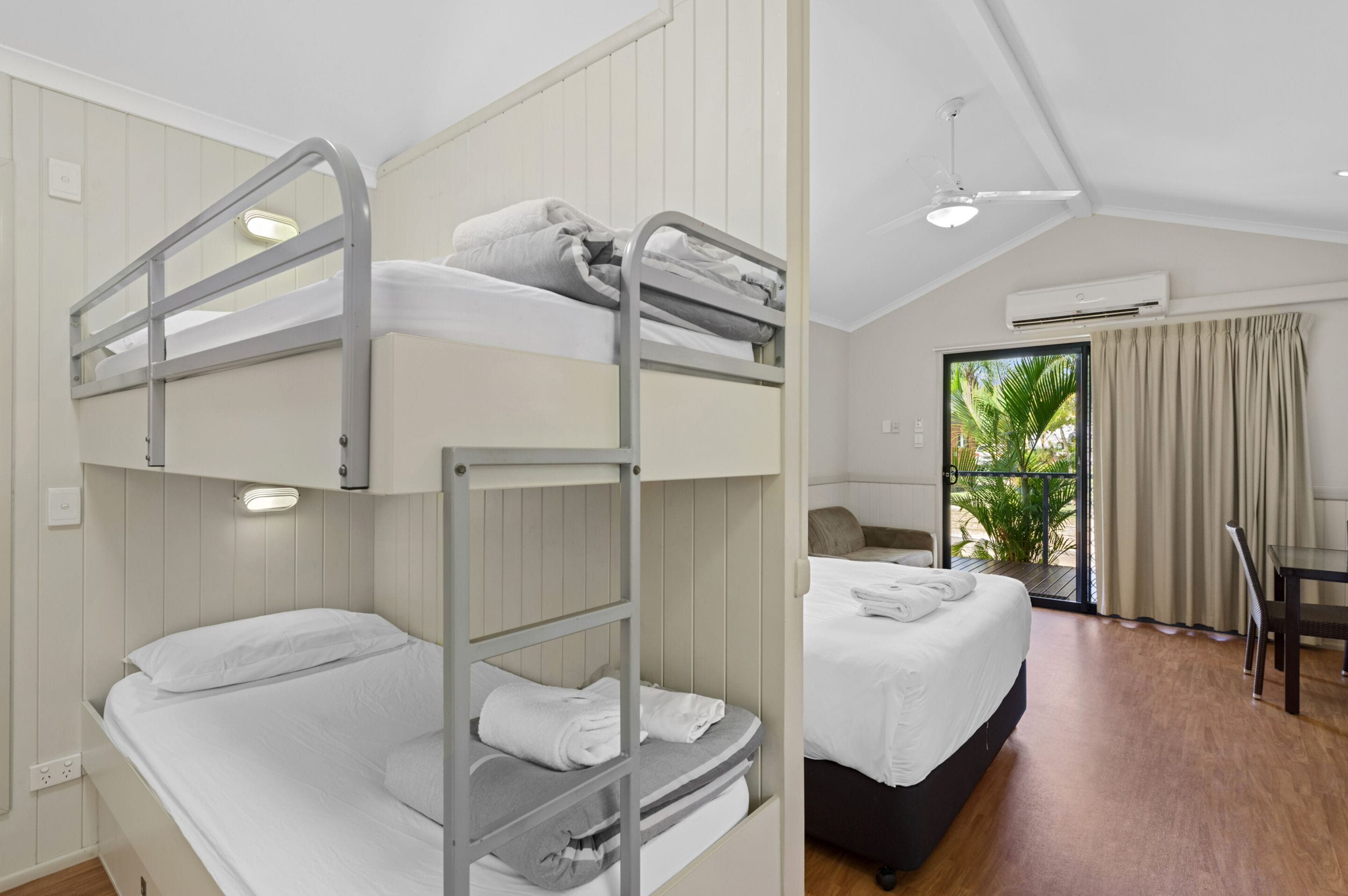 Habitación con literas, un escritorio, una silla, una ventana con cortinas e instalación de aire acondicionado.