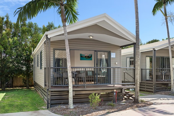 A single-story mobile home with a covered porch, outdoor seating, and a fenced patio area.