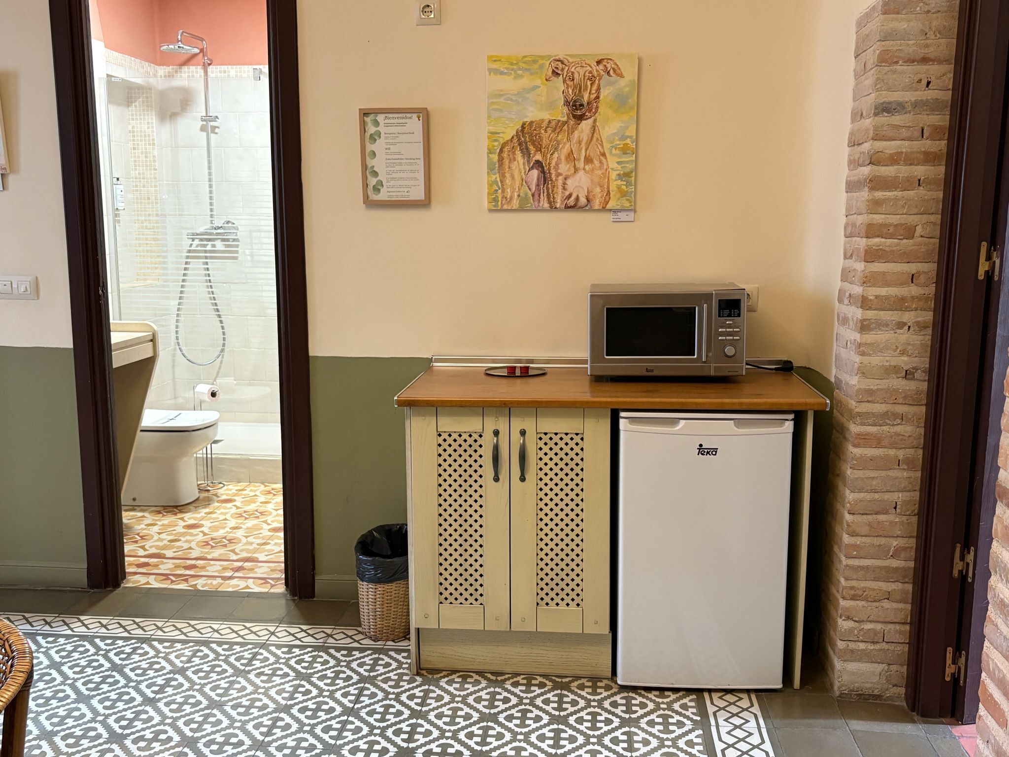 A compact bathroom with a shower, toilet, and a small kitchenette area featuring a microwave and refrigerator.